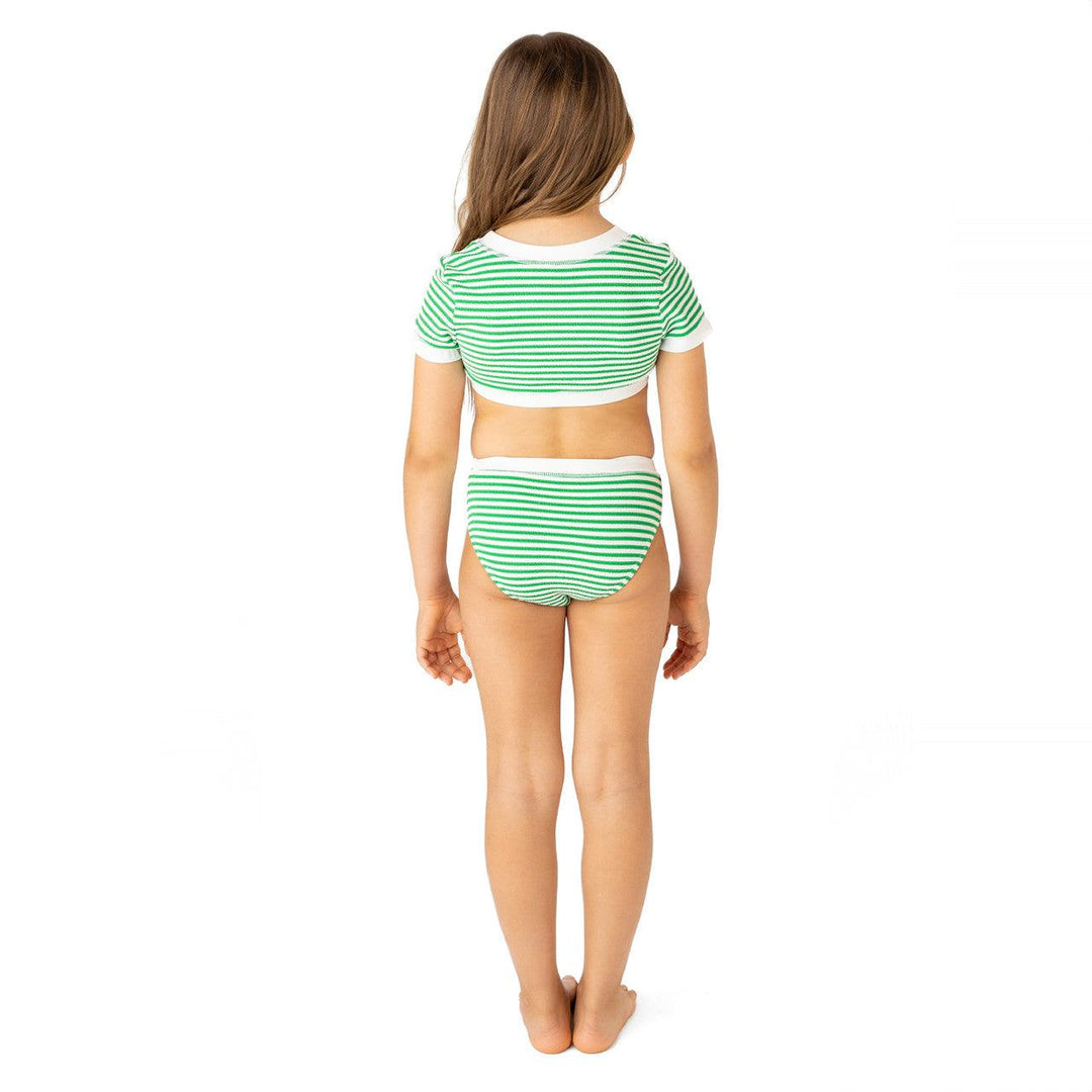 little girl wearing the bathing suit from the back. top comes up high and bottoms are bikini style 