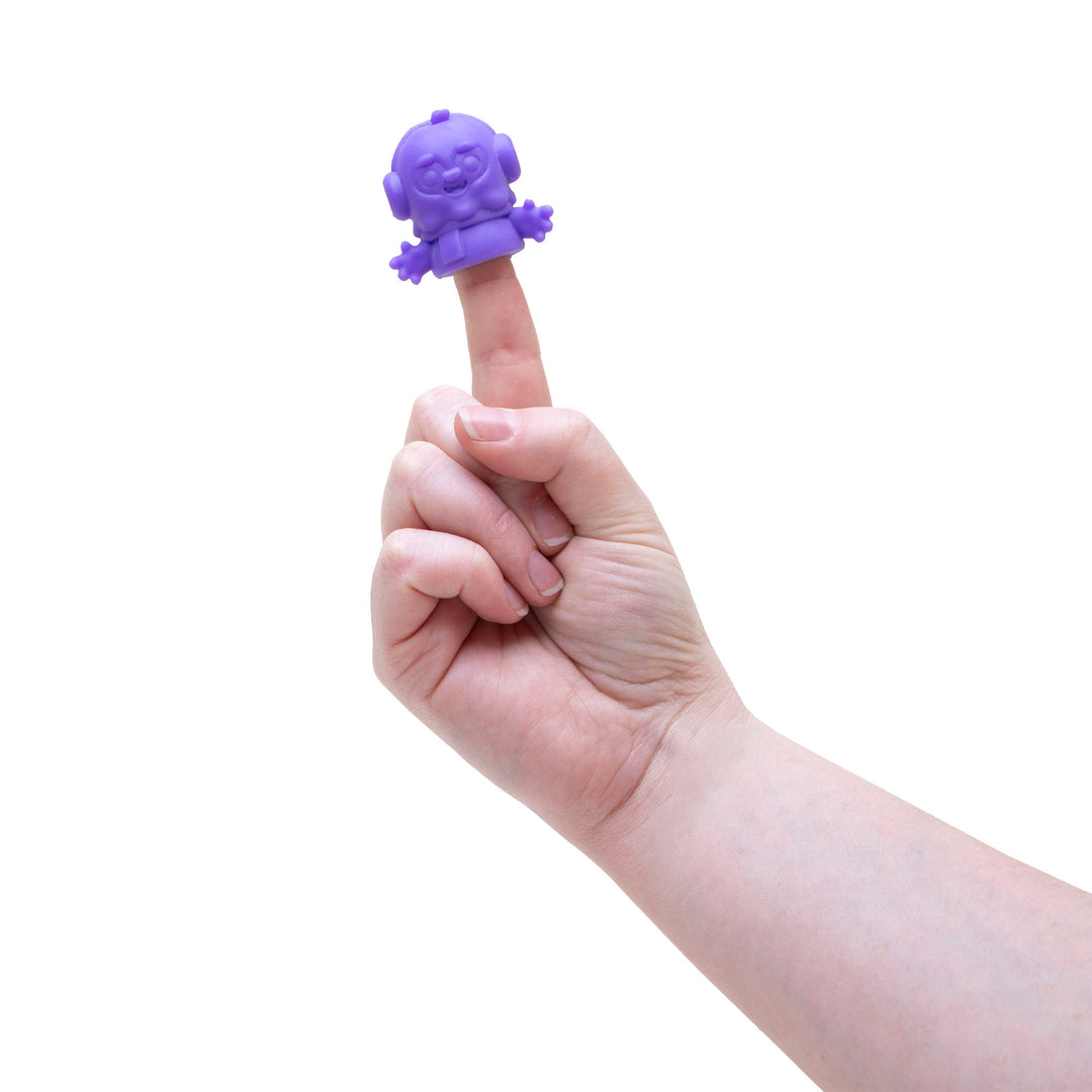 Hand holding a small purple creature toy on a finger against a white background