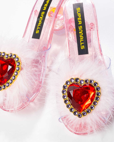 close up of the red heart on the shoe surrounded by pink feathers. this pic shows the clear plastic of the shoe and the pink bottoms. 