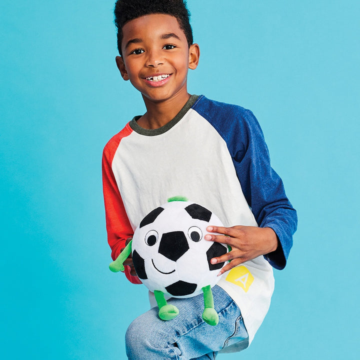 Child holding a plush soccer ball against a blue background