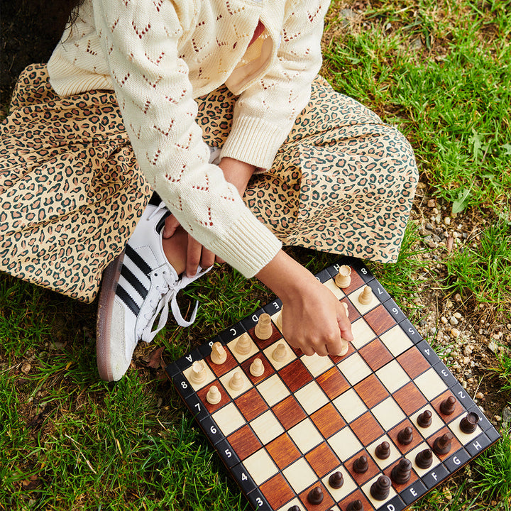 Person playing checkers on a grassy field wearing wide leg leopard pants 