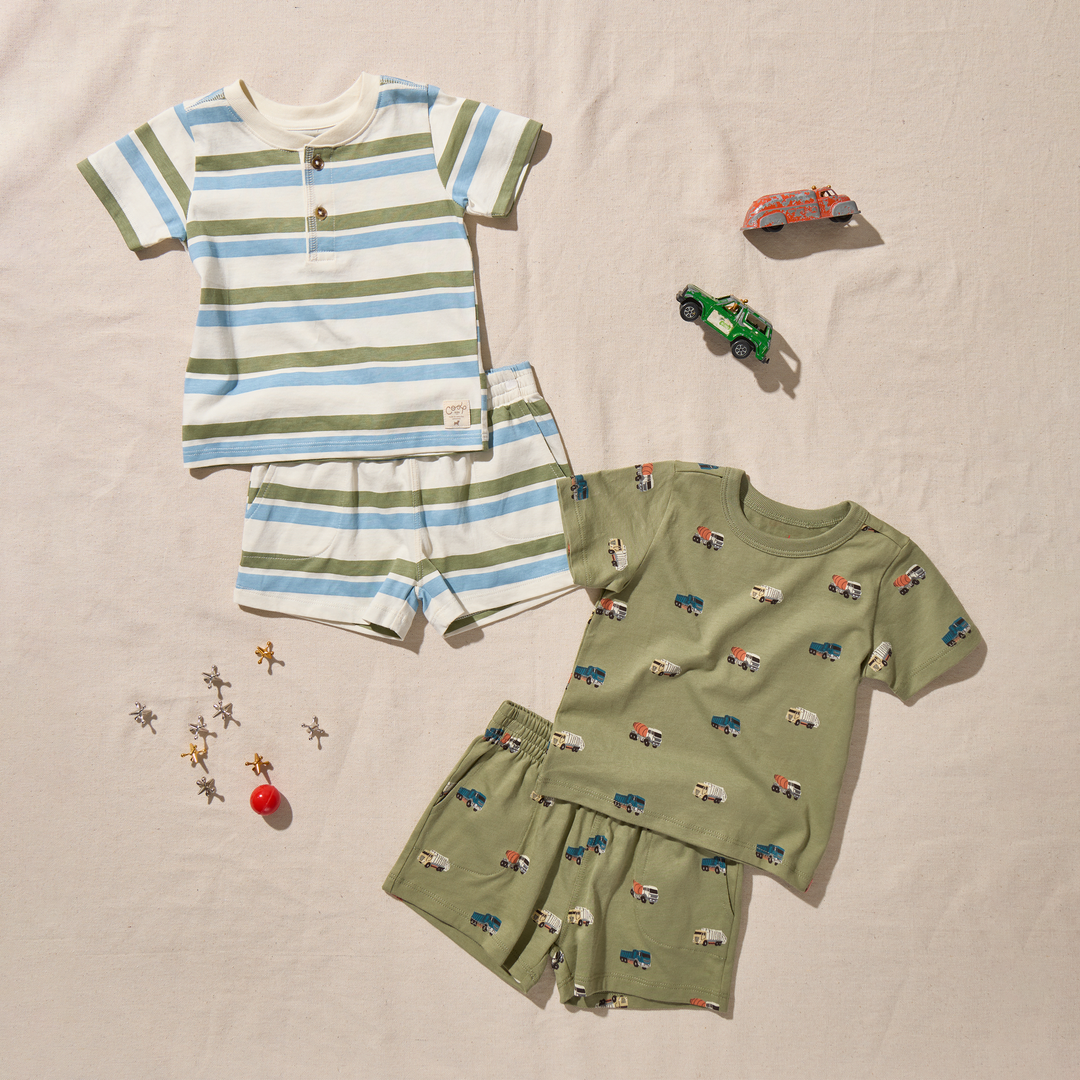 Children's clothing set with striped shirt and shorts on a beige surface.
