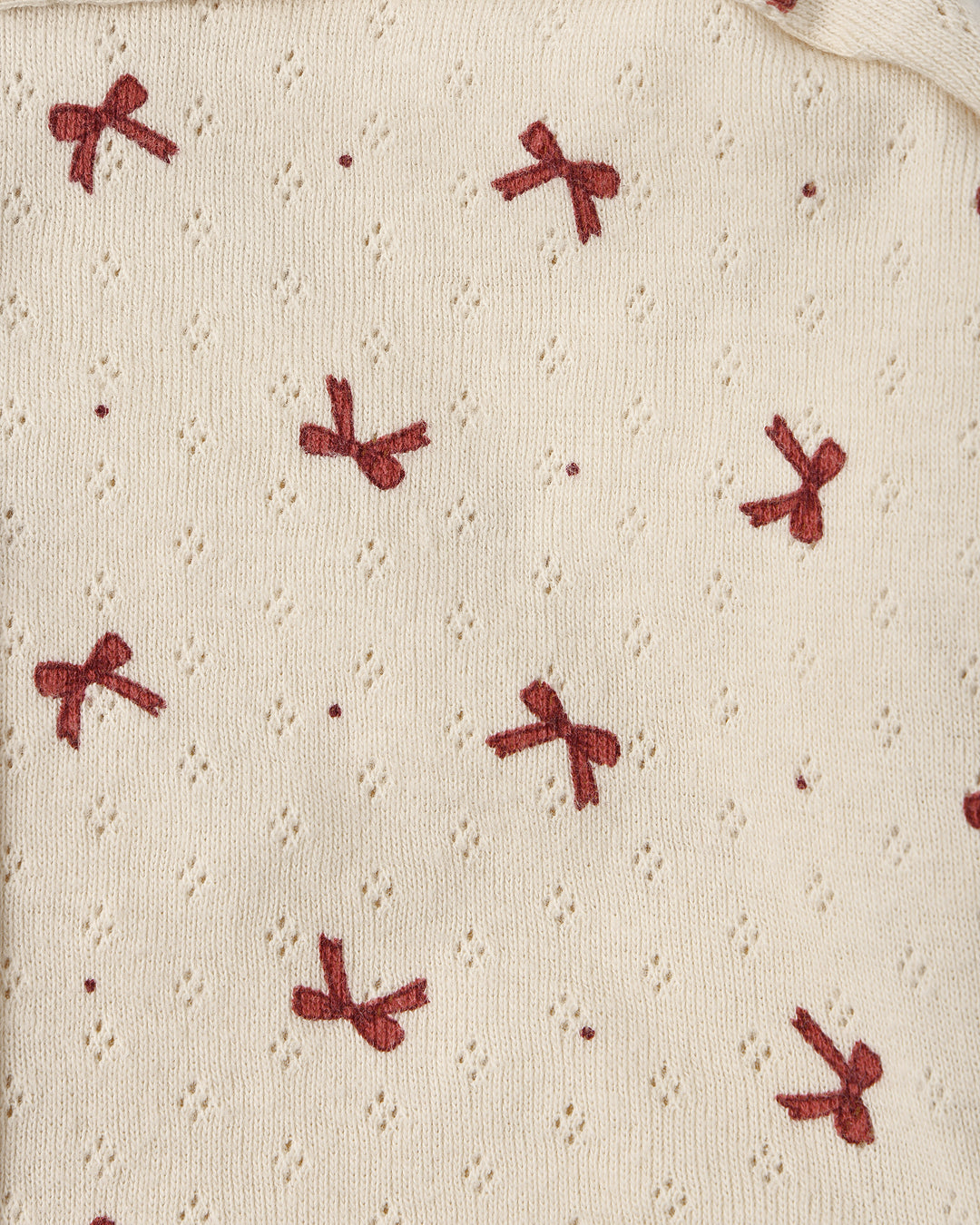 close up on the beige pointelle fabric with tiny red bows printed on it