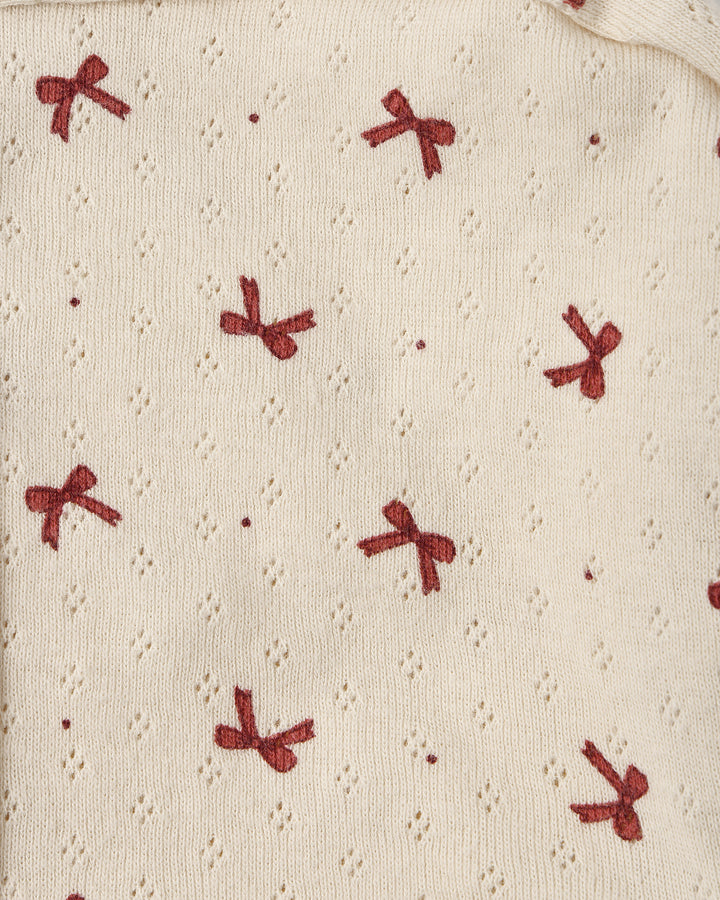 close up on the beige pointelle fabric with tiny red bows printed on it