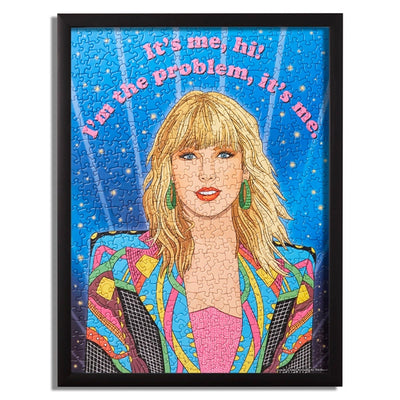 Taylor swift puzzle. Big picture of her face. She is wearing  colorful blazer and her hair is down. The saying reads " It's me, hi! I'm the problem it's me"