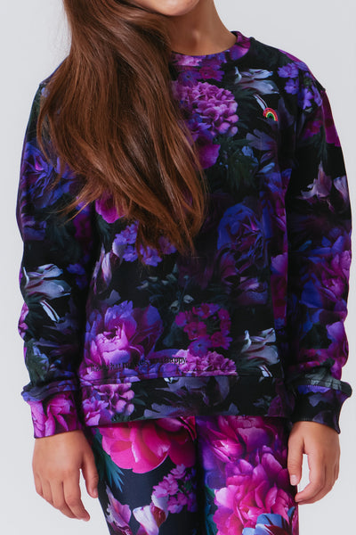 Girl wearing a long sleeve crew neck sweatshirt with multi colored purple print from Terez