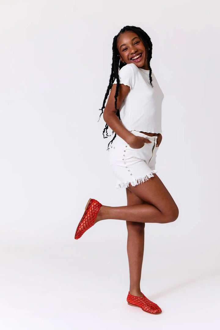 girl modeling the white cut off shorts with studs along the sides. 