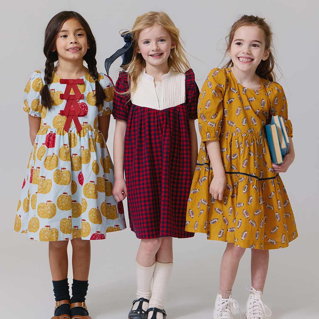 Three children wearing patterned dresses 
