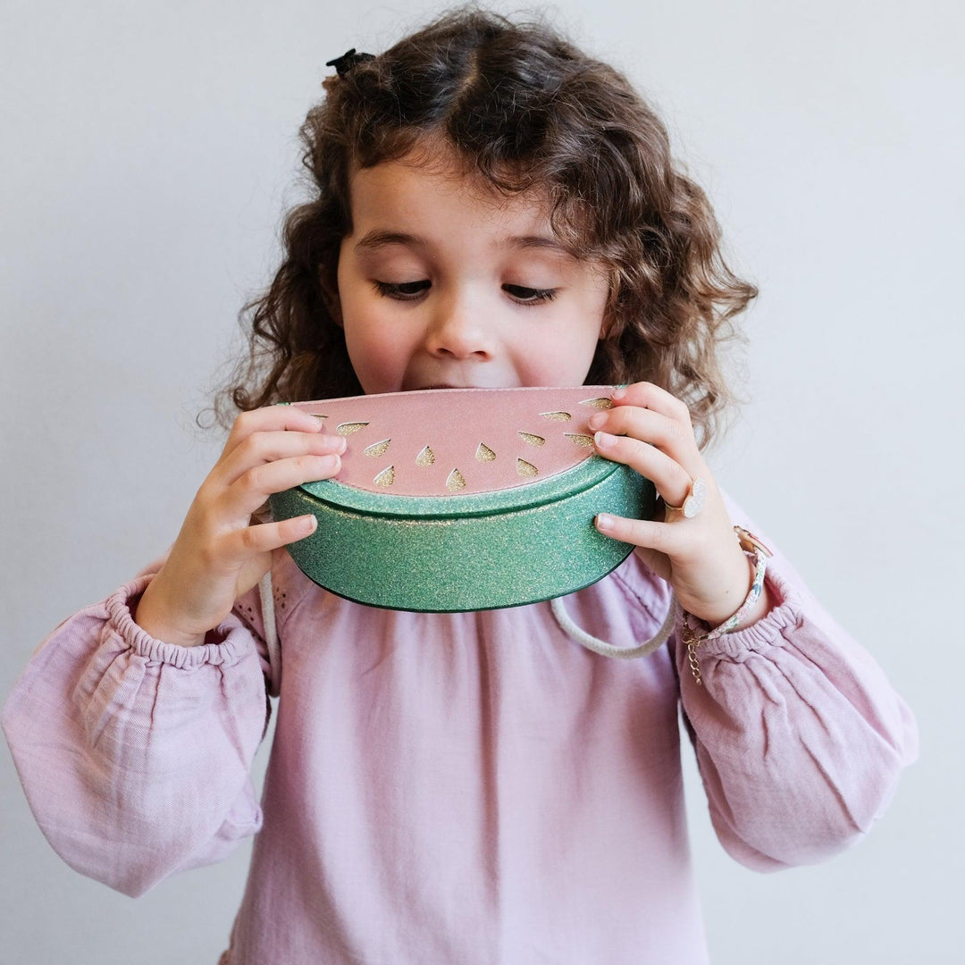 little girl modeling the bag and pretending to eat the watermelon. 