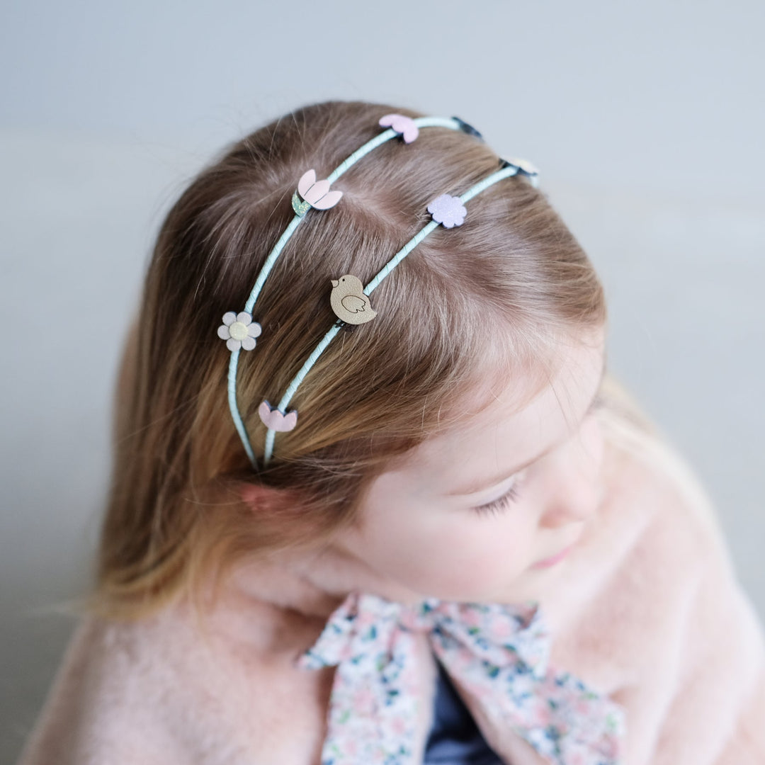 Child wearing a headband with decorative headband on a plain background