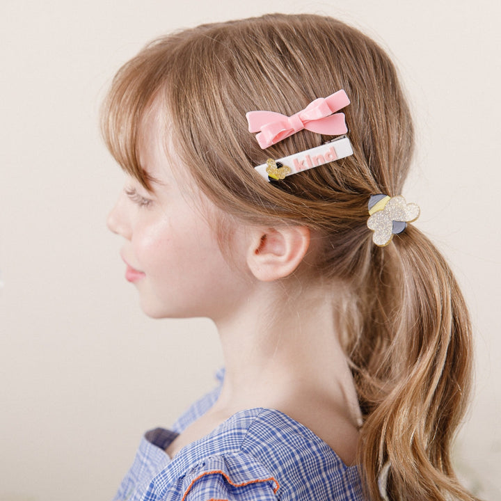 Young girl with hair styled with decorative clips on a plain background