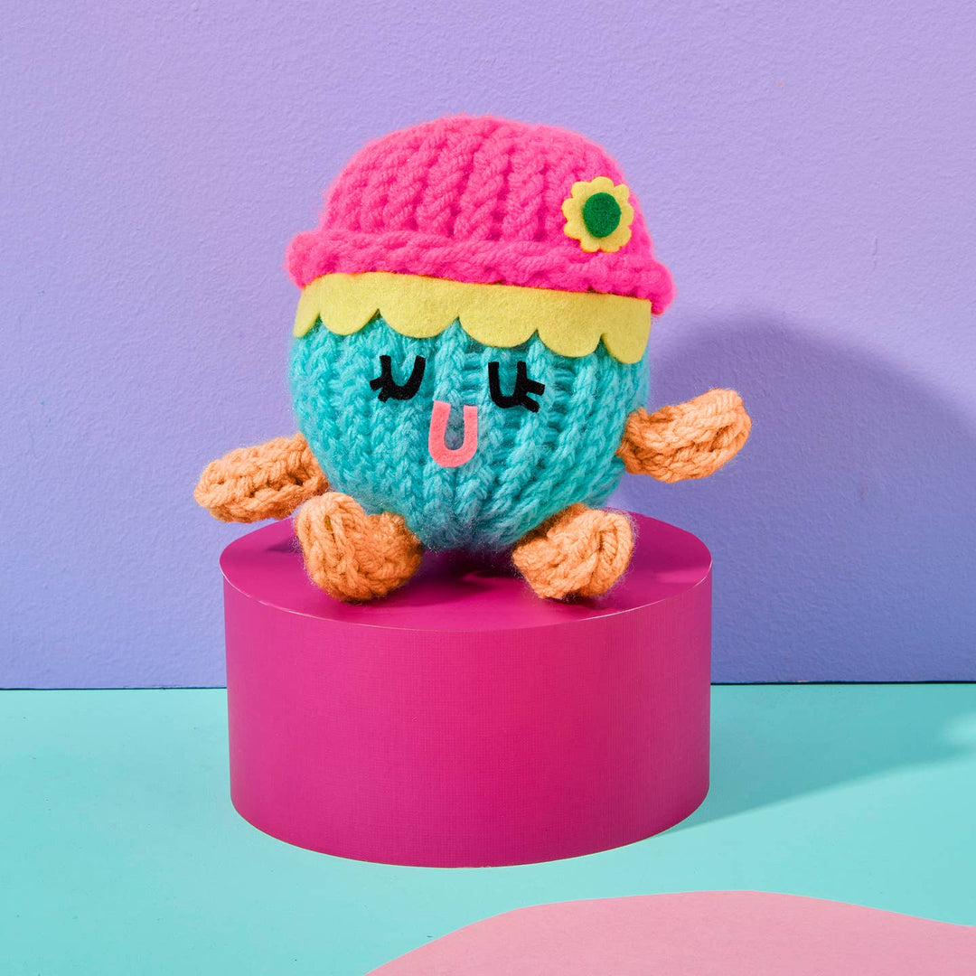 Colorful knitted toy on a pink stand with a purple background