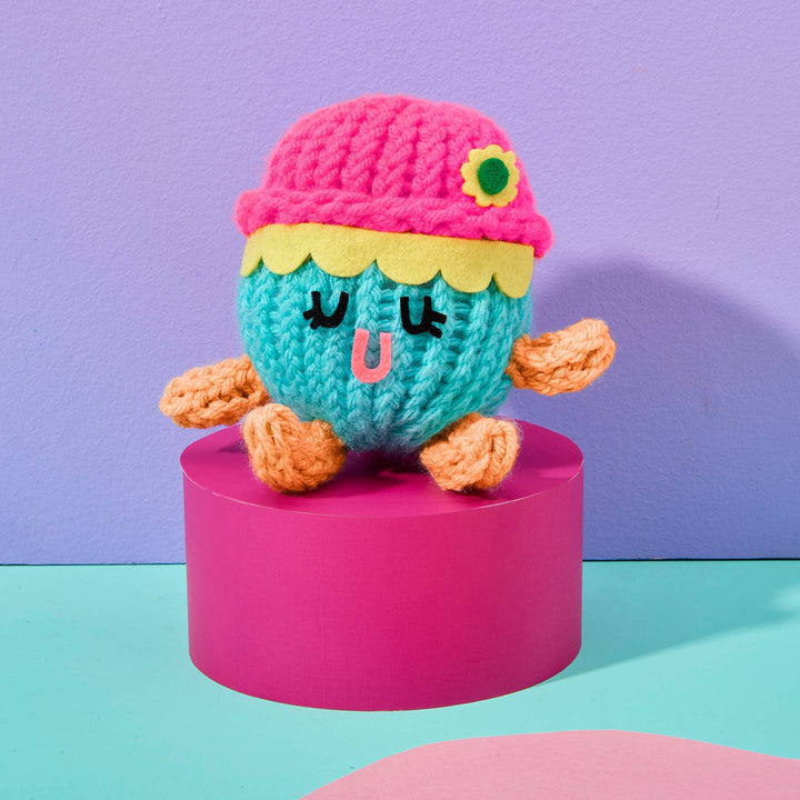 Colorful knitted toy on a pink stand with a purple background
