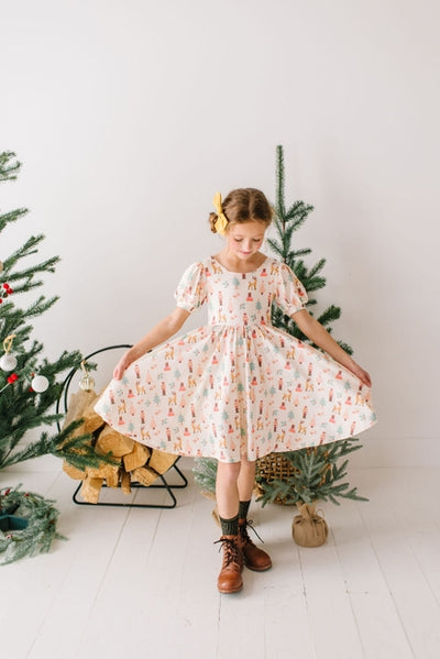 girl twirling in a biege dress with nutcracker print on the dress. puff sleeve detail. 