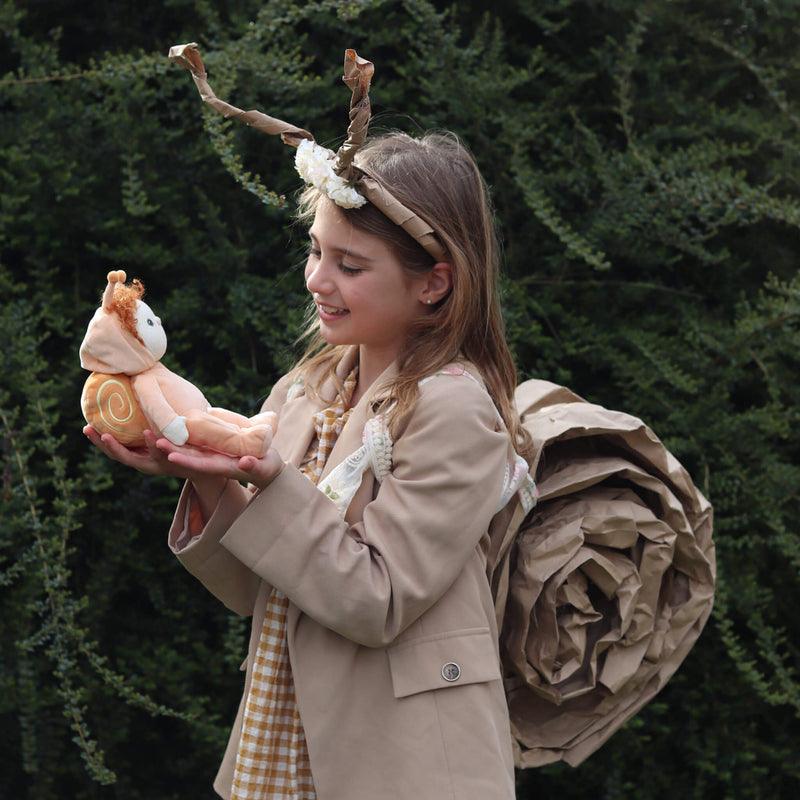 baby doll wearing a pale orange snail shell and red curly hair. 