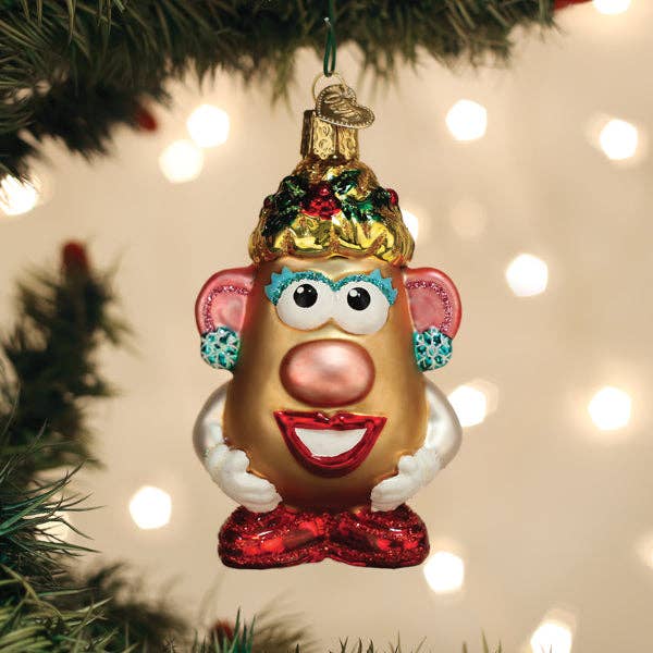 Christmas ornament shaped like a potato with a face, hanging on a tree with lights in the background.