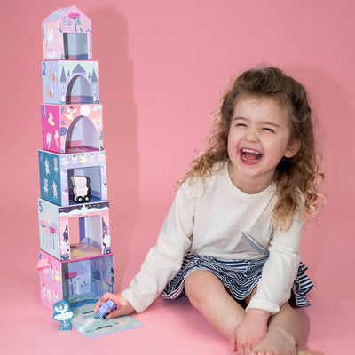 little girl sitting next to the stacking cubes showing how high they stack above the little girl's head. 