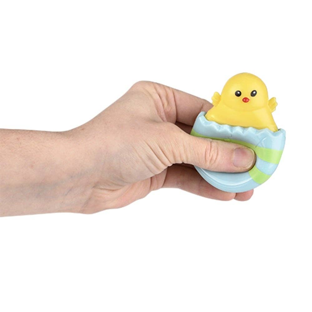Hand holding a small yellow duck toy with a striped egg on a white background