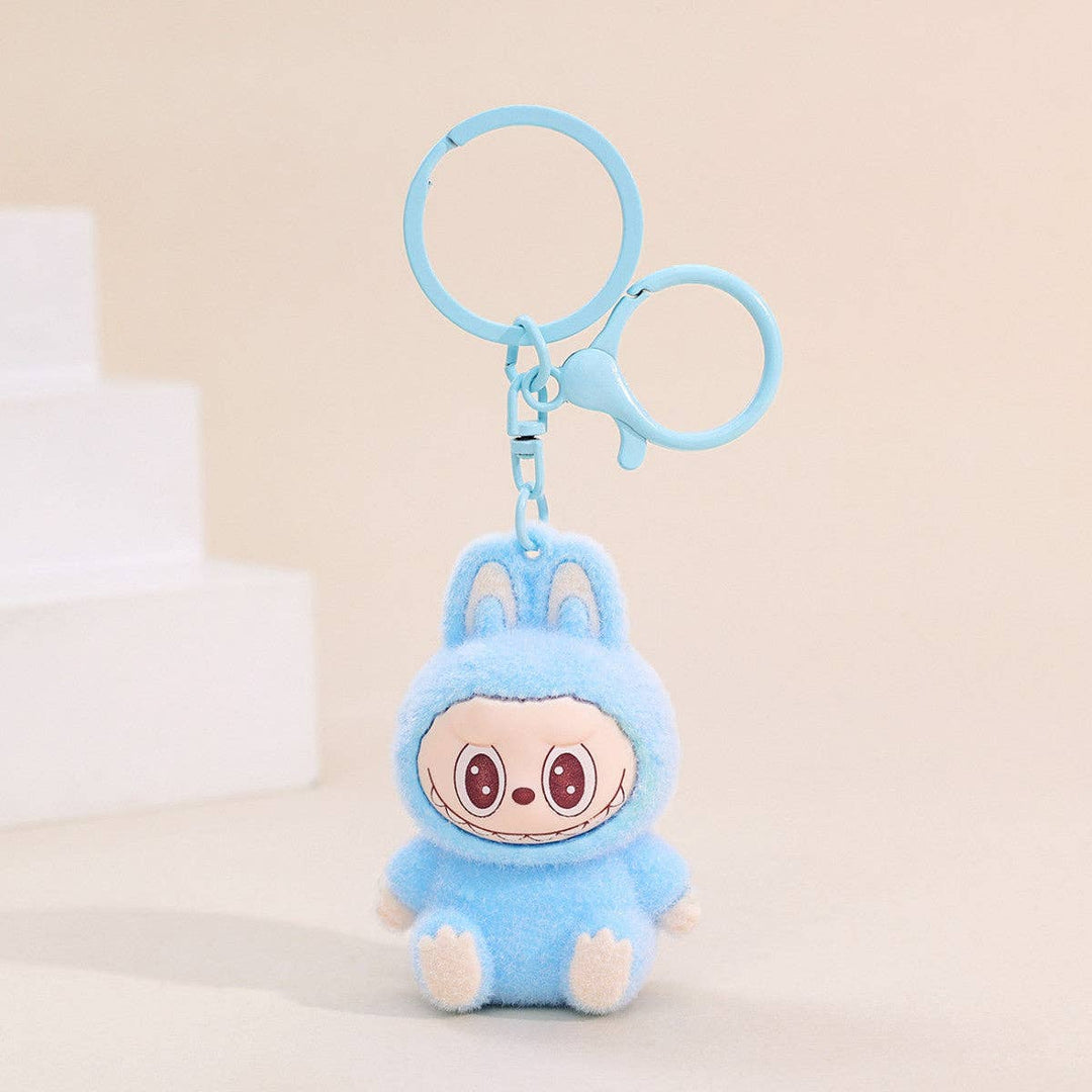 Plush keychain with a cartoon character in a blue outfit on a beige background