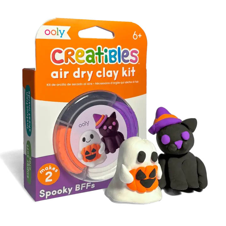 Ooly Creatibles air dry clay kit in its retail packaging, shown alongside two finished Halloween-themed clay figures: a white ghost with an orange pumpkin face and a black cat wearing a purple witch hat with purple nose and ears.