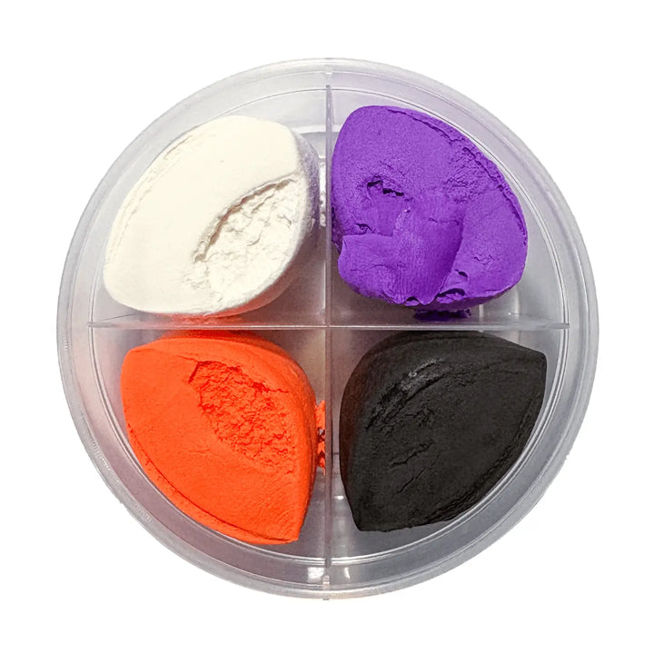 Four clay product pats arranged in a clear round divided container on a white background: white, purple, bright orange, and black.