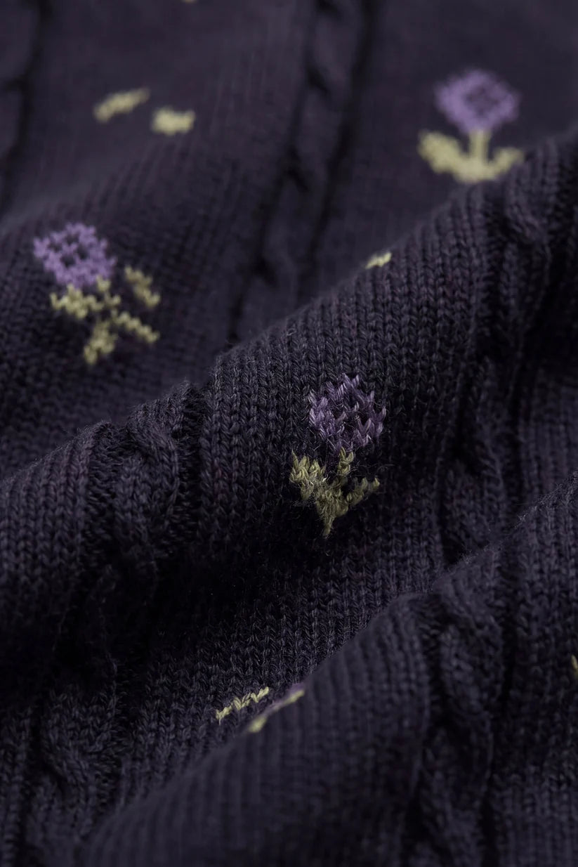 Close-up of dark purple fabric with embroidered flowers.
