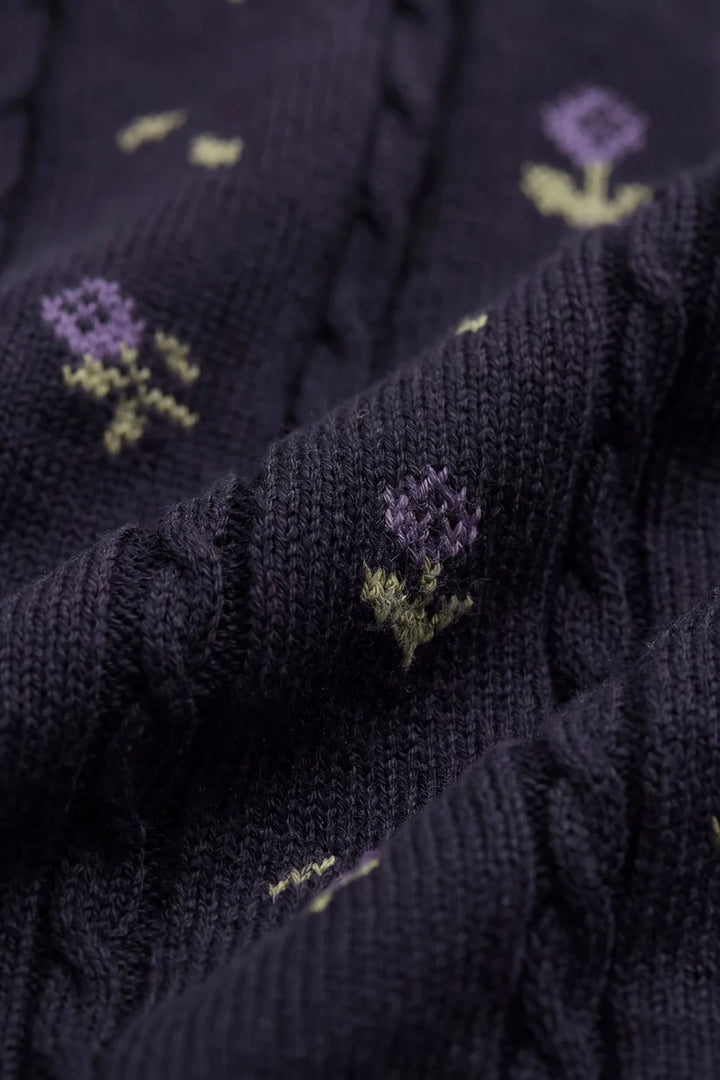 Close-up of dark purple fabric with embroidered flowers.