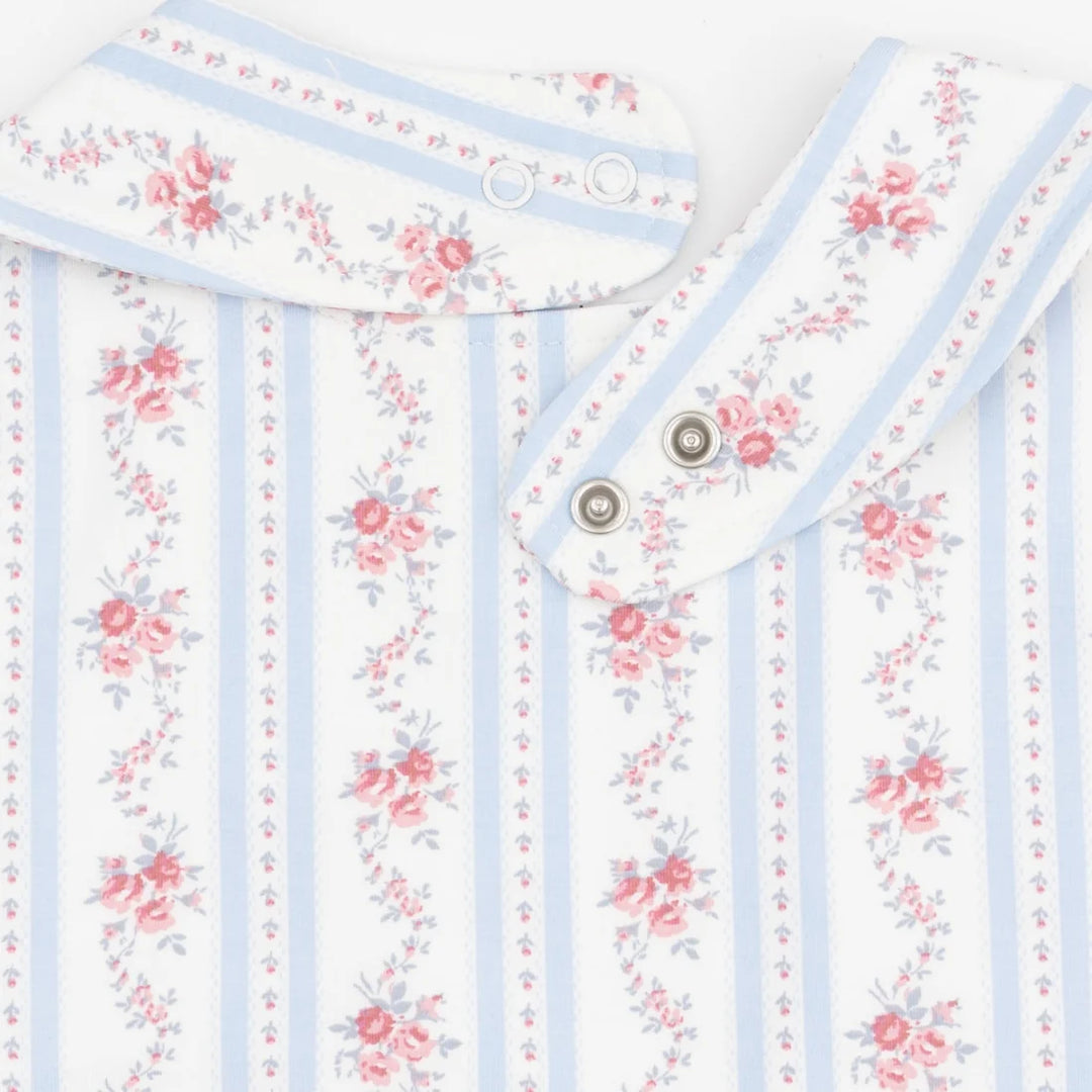 Close-up of a baby garment or textile with a white base, light blue vertical stripes, and pink floral prints. The fabric has a soft texture and is shown folded with metal snap buttons visible.