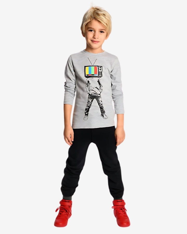 Child wearing a gray sweatshirt with a graphic design, black pants, and red shoes on a white background