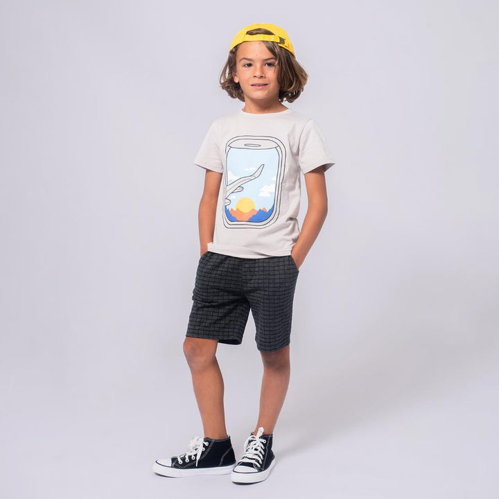 young boy modeling the black shorts with geometric squares  on them and a graphic tee. 