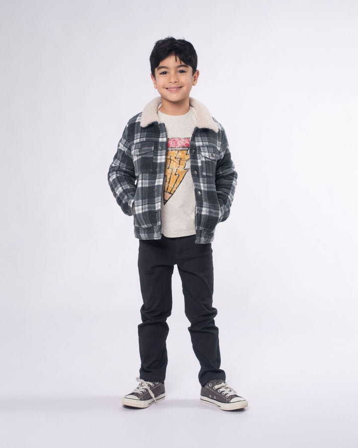 Child wearing a plaid shirt over a graphic t-shirt with black pants on a white background