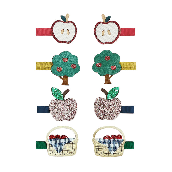 Six fabric hair clips arranged in two columns on a white background, featuring apple and basket motifs in red, yellow, green, pink, blue, and beige.