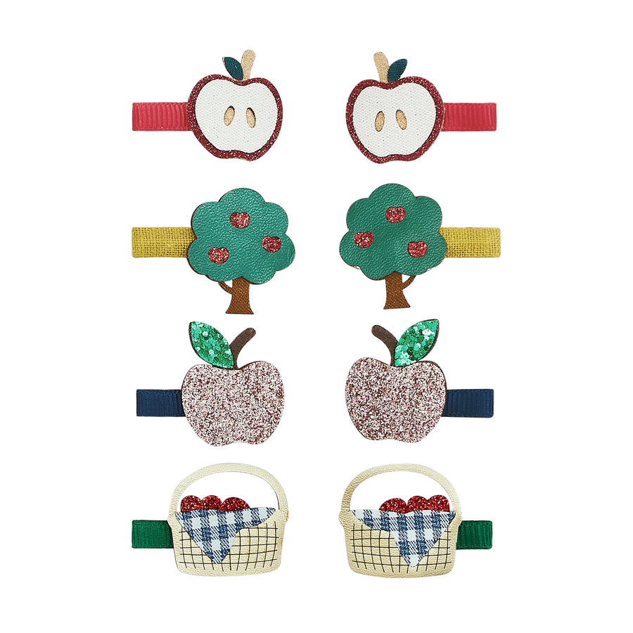 Six fabric hair clips arranged in two columns on a white background, featuring apple and basket motifs in red, yellow, green, pink, blue, and beige.