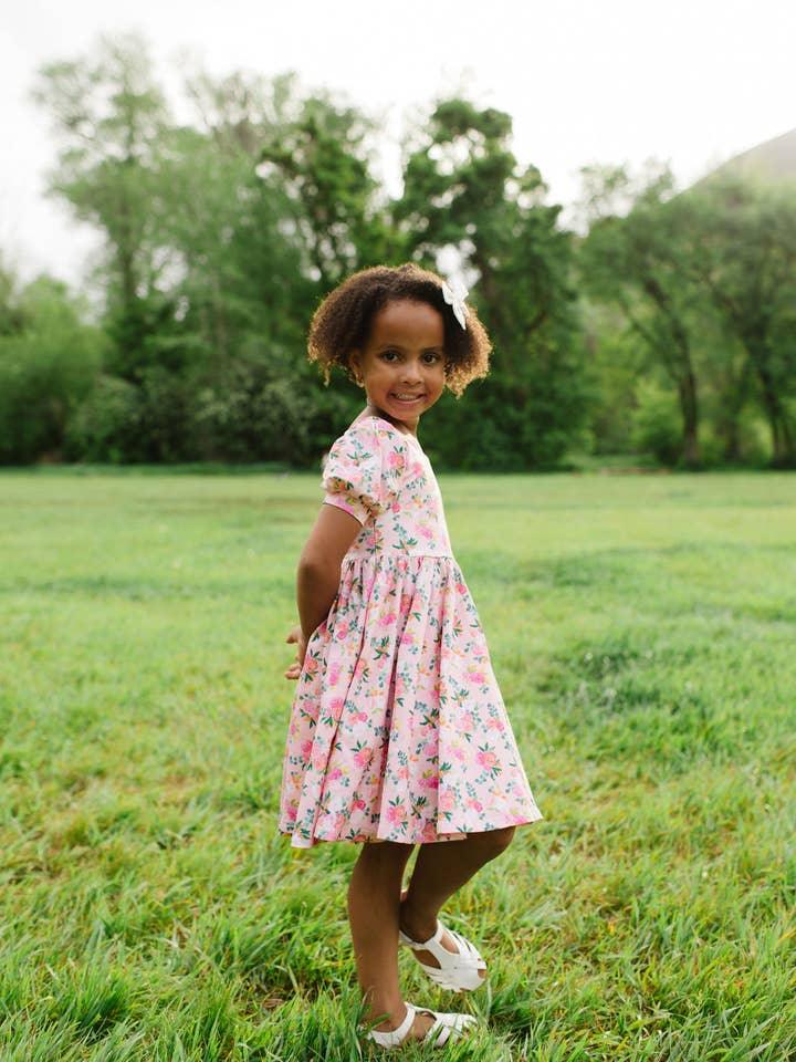 little girl modeling the peach floral puff sleeve dress with full skirt. 