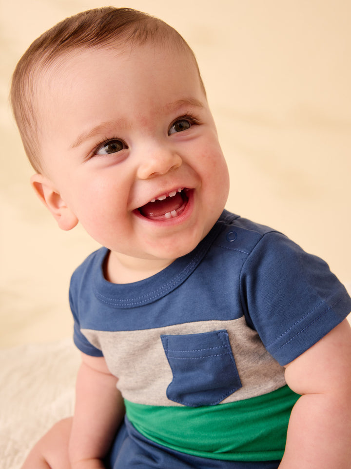 Baby wearing a colorful shirt with a plain background