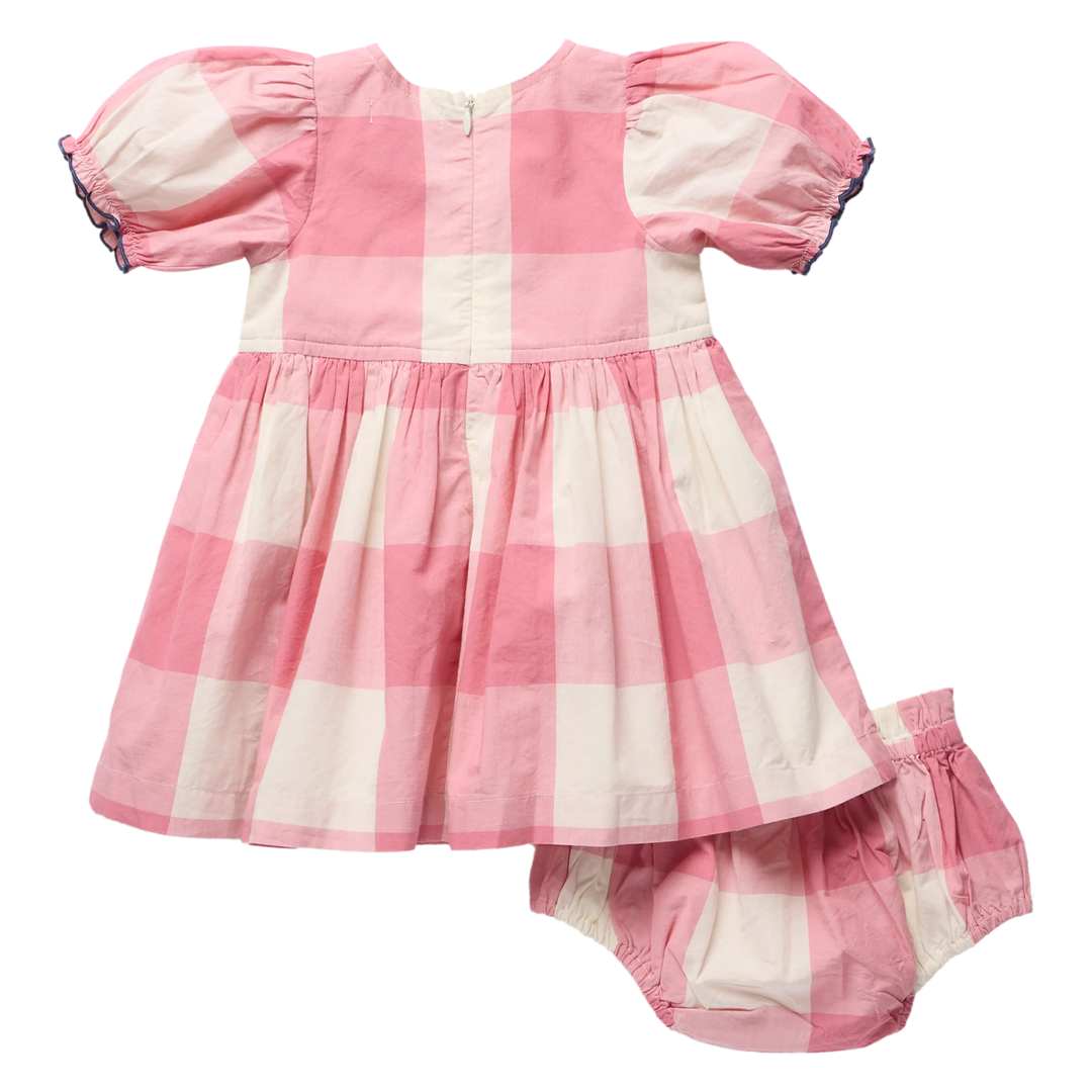 A baby girl's two-piece outfit consisting of a short-sleeve dress and matching bloomers, both featuring a pink and off-white gingham check pattern. The dress has puffed sleeves with dark blue ruffle trim, and the matching bloomers have elastic leg openings.
