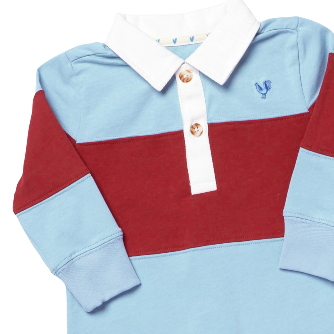 A long-sleeve children's polo shirt with a color-blocked design featuring light blue, deep red, and white sections, with a white collar and gold buttons.