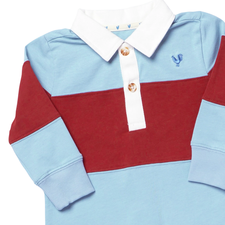 A long-sleeve children's polo shirt with a color-blocked design featuring light blue, deep red, and white sections, with a white collar and gold buttons.