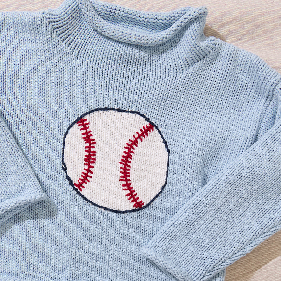 Light blue knitted sweater with a baseball design on a beige background