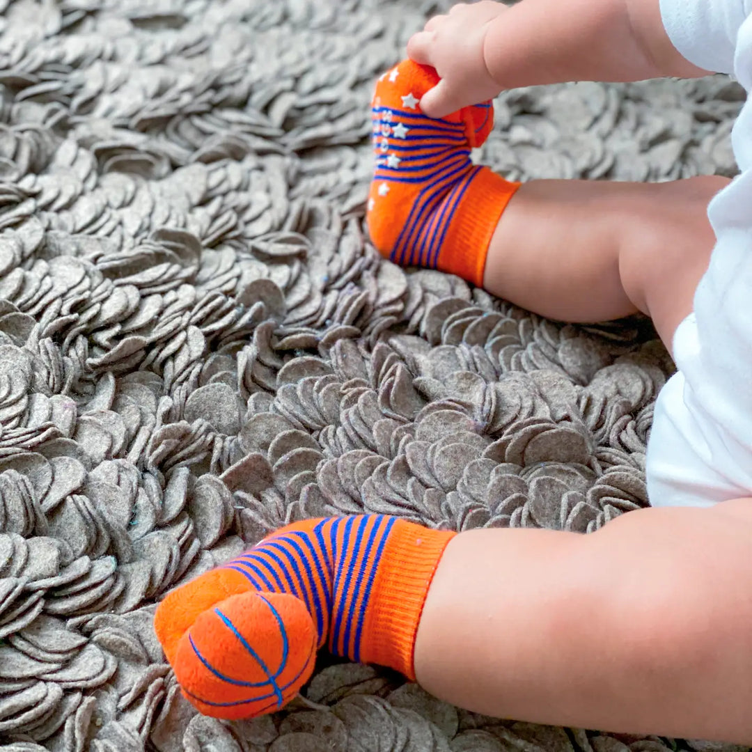 baby wearing the baby socks with tiny basketballs attached. 