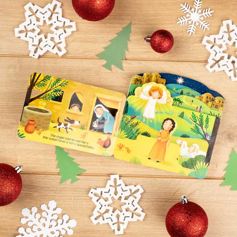 Two children's books on a wooden surface with Christmas decorations