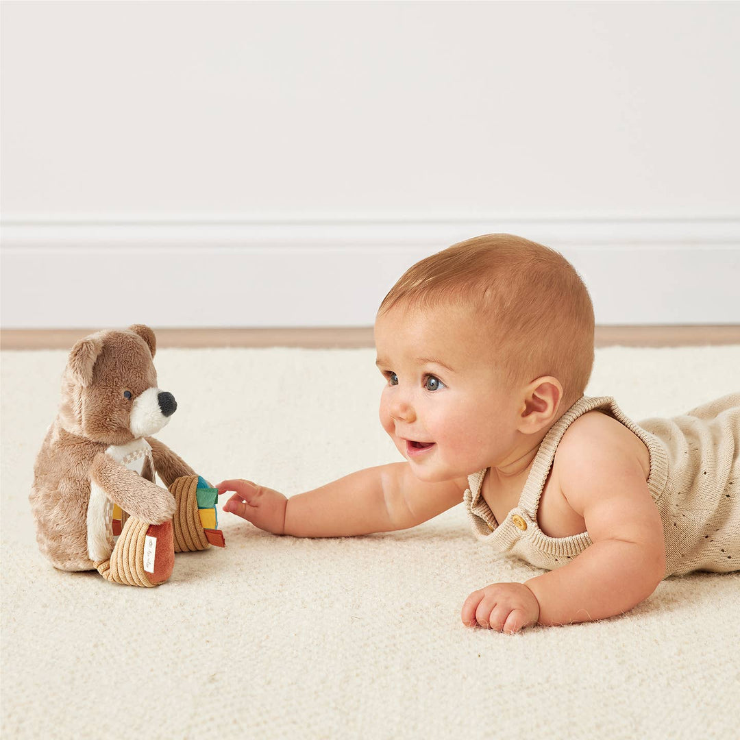 Baby lying on a carpeted floor with a plush toy
