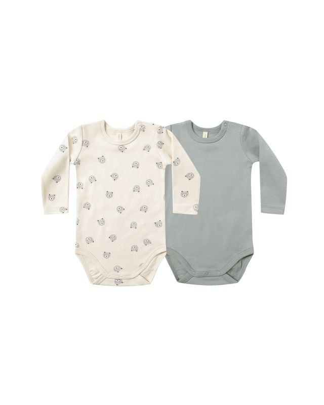 Two baby bodysuits, one cream with a bear pattern and one blue/gray, on a white background.