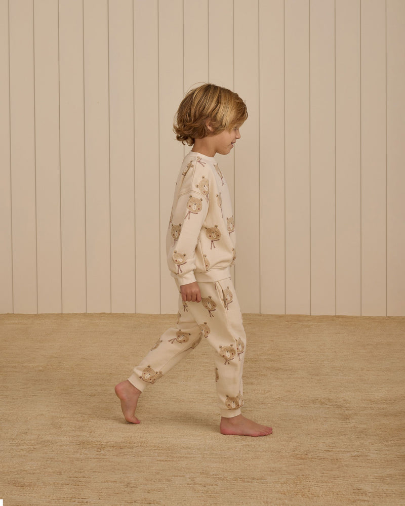 picture of boy walking with the bear set on it. Bear heads wearing red scarf. 