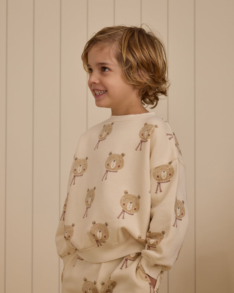 close up of young boy wearing the bears sweatsuit. crewneck sweatshirt with bears wearing a scarf all over the set. 