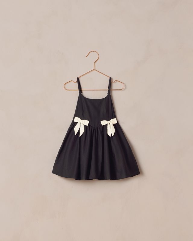 Black dress with white bows on a beige background