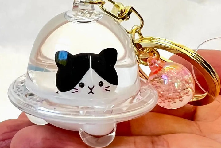 Keychain with a cat design inside a transparent UFO keychain