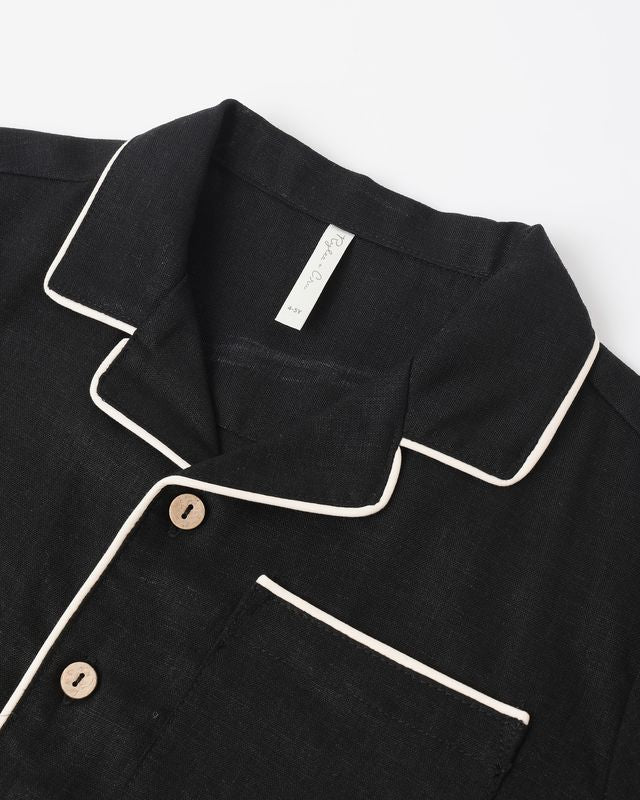 close up on the details of a black button down with white piping 