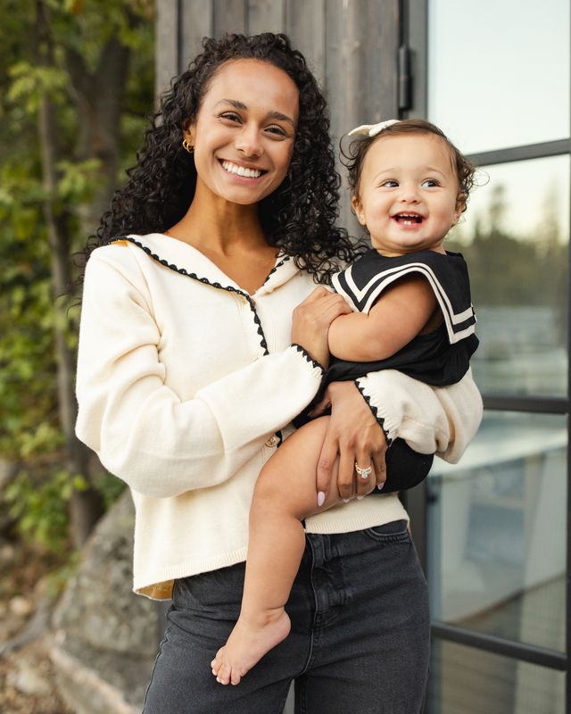 Woman holding a baby outdoors with a blurred background