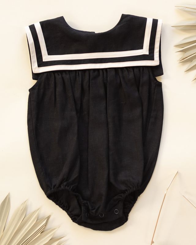 Black baby sailor romper with white trim on a light background